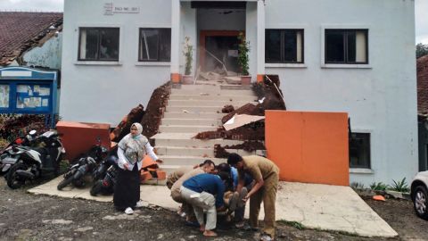 Pejabat kota di Cianjur mengevakuasi seorang rekan yang terluka setelah gempa.