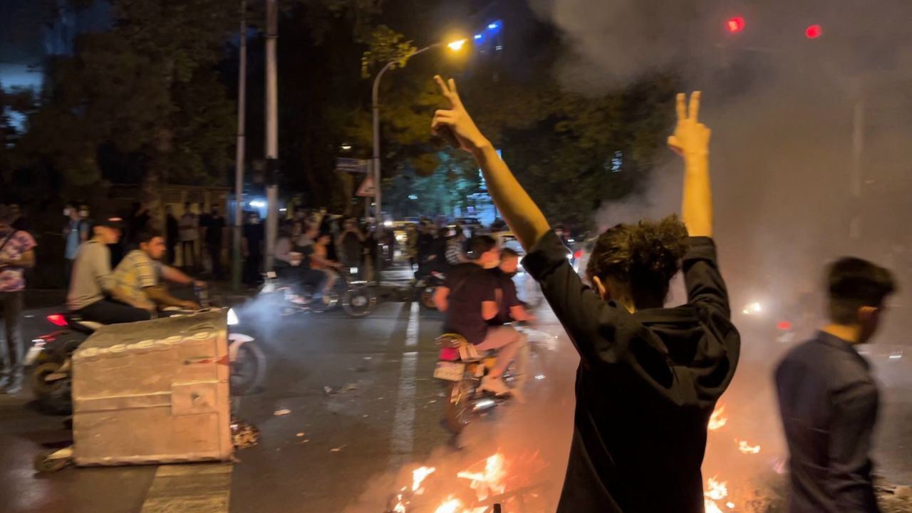 TOPSHOT - A picture obtained by AFP outside Iran shows shows a demonstrator raising his arms and makes the victory sign during a protest for Mahsa Amini, a woman who died after being arrested by the Islamic republic's "morality police", in Tehran on September 19, 2022. - Fresh protests broke out on September 19 in Iran over the death of a young woman who had been arrested by the "morality police" that enforces a strict dress code, local media reported. Public anger has grown since authorities on Friday announced the death of Mahsa Amini, 22, in a hospital after three days in a coma, following her arrest by Tehran's morality police during a visit to the capital on September 13. (Photo by AFP) (Photo by -/AFP via Getty Images)