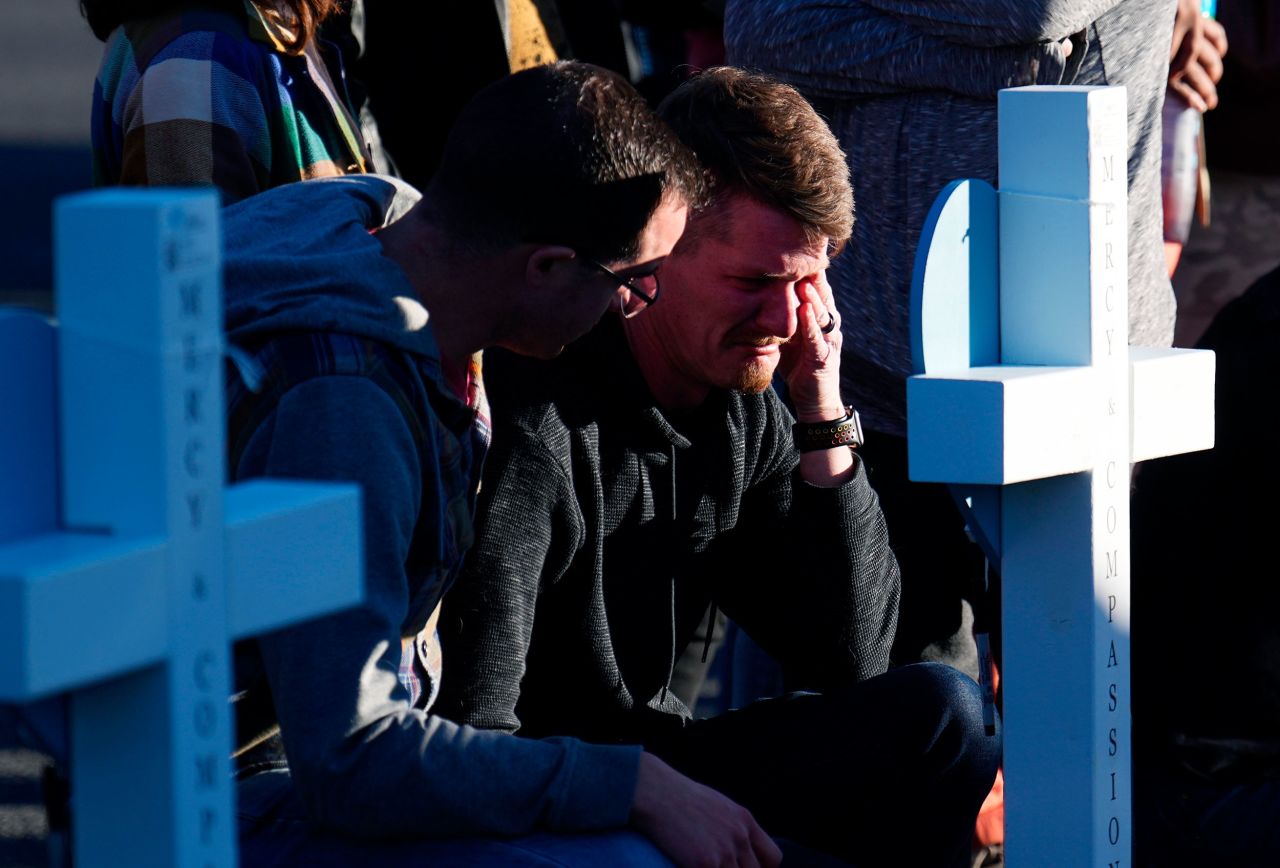 A man is comforted while crying at a makeshift memorial on Monday, November 21, near the site of a mass shooting at an LGBTQ club in Colorado Springs, Colorado.