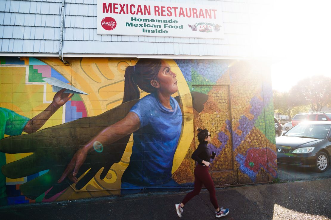 A woman jogs past the first mural depicting Latino presence in Chattanooga, painted on the side of Latino grocery store Carniceria Loa #7.