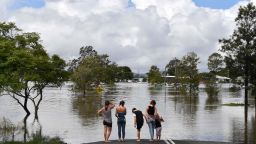 TOPSHOT - A family stays next to a flooded street in Lawrence, some 70 kms from the New South Wales town of Lismore, on March 1, 2022. (Photo by SAEED KHAN / AFP) (Photo by SAEED KHAN/AFP via Getty Images)