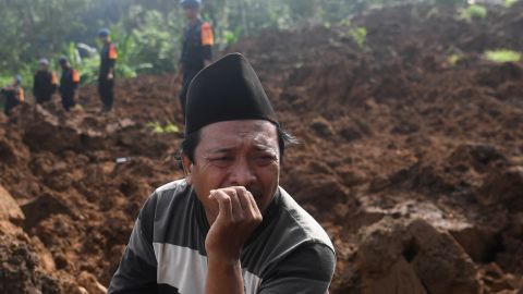 22 Kasım 2022, Endonezya, Batı Java, Cianjur'da Pazartesi günü meydana gelen depremin ardından toprak kaymasının vurduğu bir bölgede kurtarma ekipleri kurbanları ararken bir adam tepki gösteriyor.