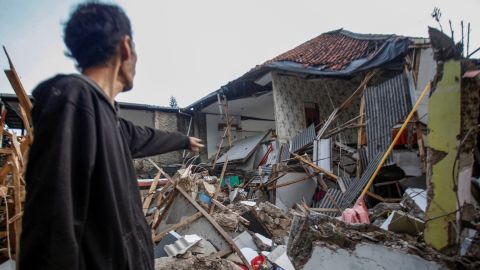 2022 年 11 月 21 日，一名男子站在印度尼西亞西爪哇省 Cianjur 發生地震後受損的房屋附近。