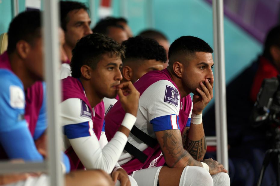 Costa Rica players watch the Spain match from the bench.