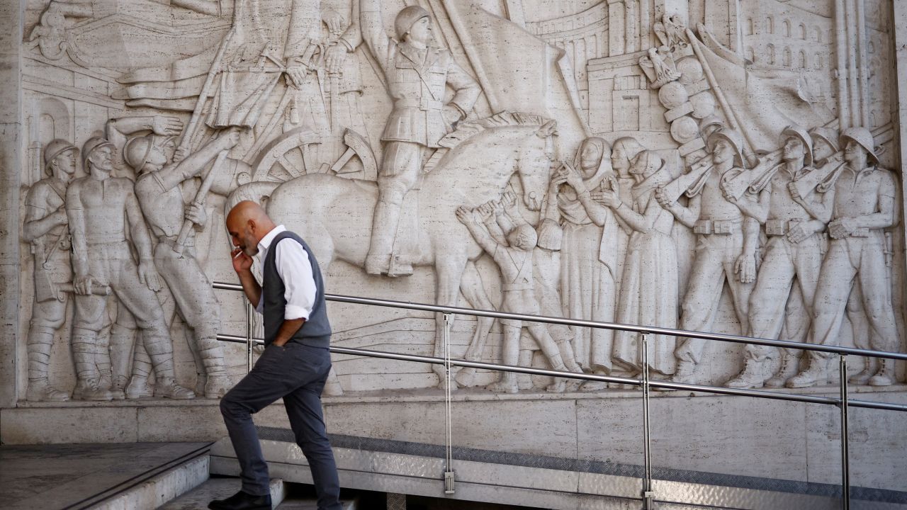 A man walks past a bas-relief depicting fascist leader Benito Mussolini in the EUR neighborhood of Rome, Italy, known for its fascist architecture.