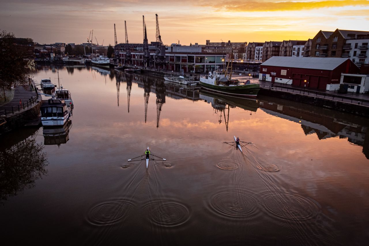 The sun rises over Bristol, England, as rowers cross the basin past the old docks on Sunday, November 20.