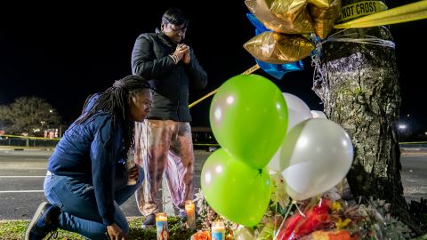 Lashana Hicks (left) joins other mourners Wednesday at a memorial for those killed in a mass shooting at a Walmart Supercenter in Chesapeake, Virginia.