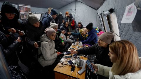Anwohner laden ihre Geräte auf, nutzen die Internetverbindung und wärmen sich am 24. November 2022 in einer Notunterkunft in Kiew auf.