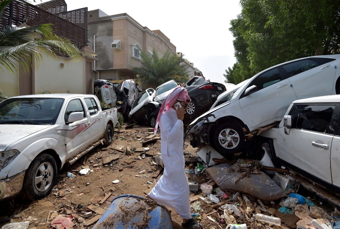 A man walks past cars piled up in a street after they were washed away by heavy rains in the Saudi coastal city of Jeddah on Friday. At least two people died the day before as heavy rains hit western Saudi Arabia, delaying flights and forcing schools to close, officials said. 
