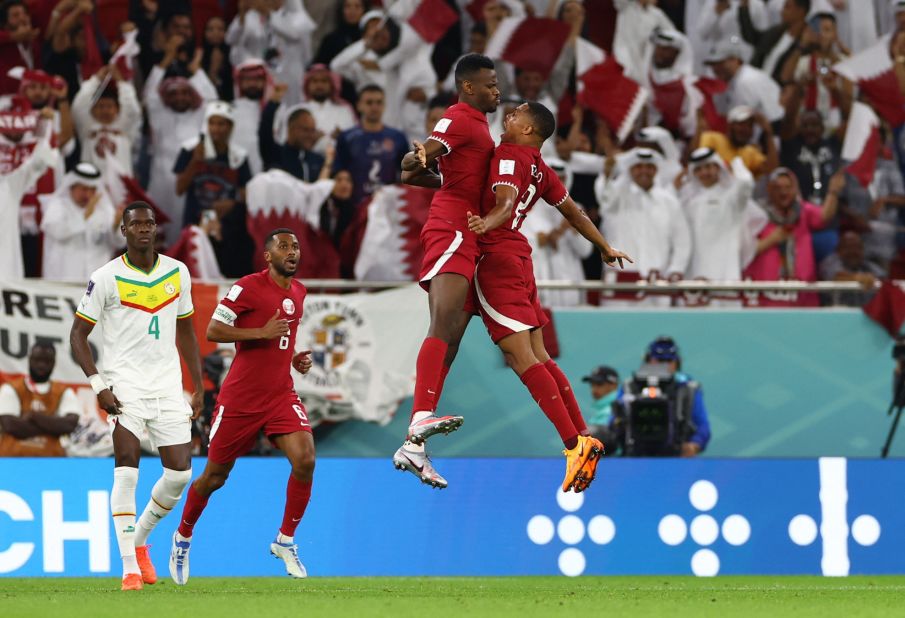 Mohammed Muntari, center, celebrates after scoring Qatar's first-ever World Cup goal. Muntari headed home a cross in the 78th minute to cut Senegal's lead to 2-1.
