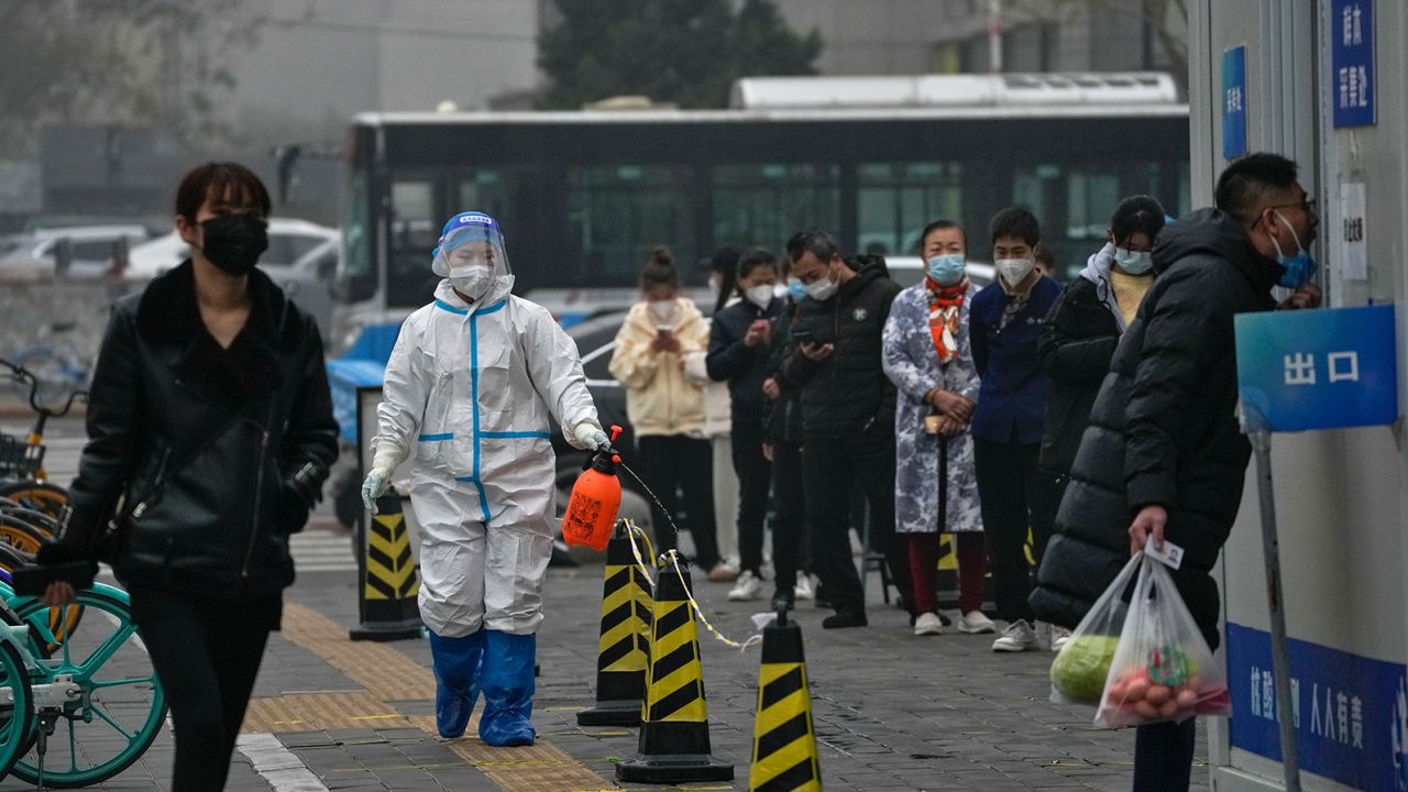 A worker in a protective suit sprays disinfectant as residents stand in line for their routine Covid-19 tests at a coronavirus testing site in Beijing on Thursday, November 24, 2022.