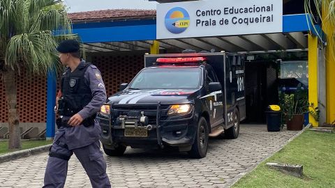 Police officers stand at the entrance of the Praia de Coqueiral Educational Center, one of two schools where a shooting took place.