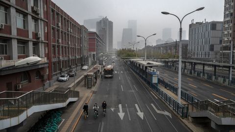 Pessoas andam de bicicleta em uma rua vazia perto do distrito comercial central de Pequim em 24 de novembro. 