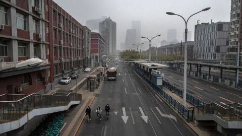 People ride bikes on an empty street near Beijing's central business district on November 24.