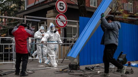 Robotníci vztyčujú kovové zábrany pred uzavretou komunitou v Pekingu 24. novembra.