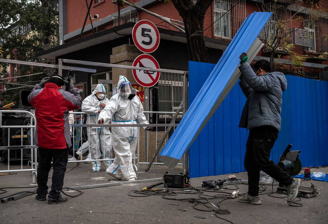 Epidemic control workers wear protective suits as they help workers erect a metal barrier fence outside a community under lockdown to prevent the spread of Covid-19 on November 24, 2022 in Beijing, China.