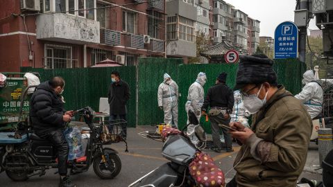 Funcionários da Covid com trajes de proteção ajudam os motoristas de entrega a entregar mercadorias para residentes em confinamento em Pequim em 24 de novembro.