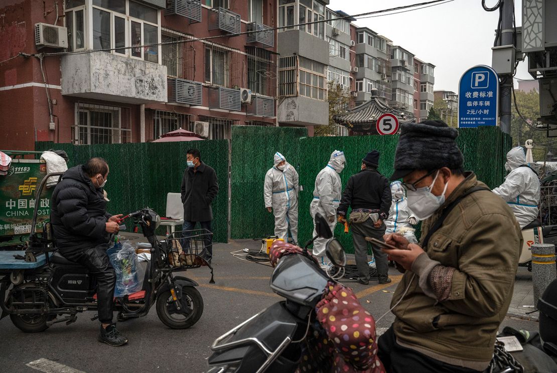 Hazmat-suited Covid workers help delivery drivers drop goods for residents under lockdown in Beijing on November 24.