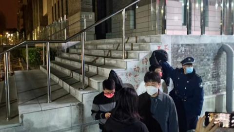 يحاول حارس أمن تغطية شعار احتجاج خالٍ من الفيروسات في حرم جامعة بكين في بكين.