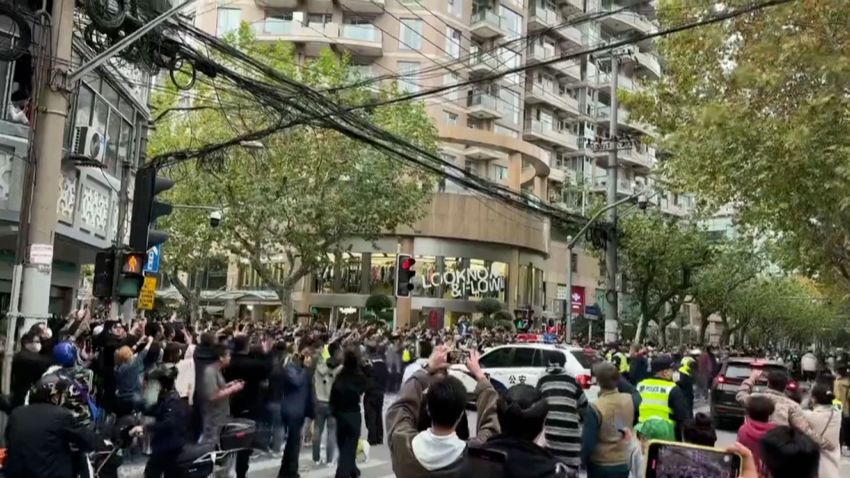 Eine Menschenmenge umringt ein Polizeifahrzeug in Shanghai, China.