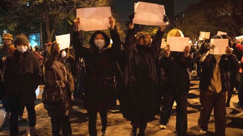 Protesters hold up blank papers and chant slogans as they march in protest in Beijing on Sunday night.
