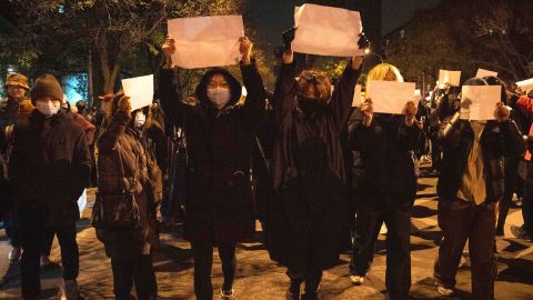 Protesters hold up blank papers and chant slogans as they march in protest in Beijing on Sunday night. 