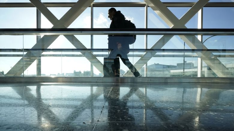 A traveler walks along a moving walkway between terminals at Logan International Airport in Boston, the day before Thanksgiving, Wednesday, Nov. 23, 2022. (AP Photo/Steven Senne)
