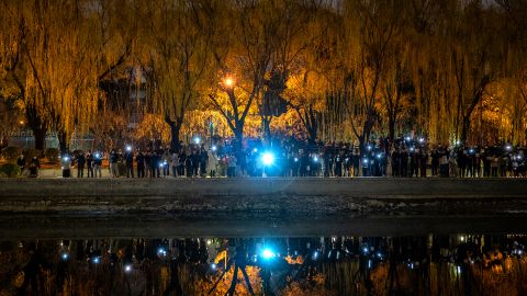 Protesters hold their mobile phones during a protest against China's strict anti-Covid measures at the Liangma River on November 27, 2022 in Beijing, China. 