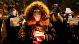 A person holds a candle, as people gather for a vigil and hold white sheets of paper in protest of coronavirus disease (COVID-19) restrictions, during a commemoration of the victims of a fire in Urumqi, as outbreaks of the coronavirus disease continue in Beijing, China, November 27, 2022. REUTERS/Thomas Peter 