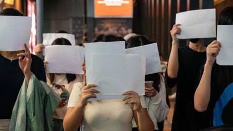 People hold white papers in Hong Kong to comment on government censorship.