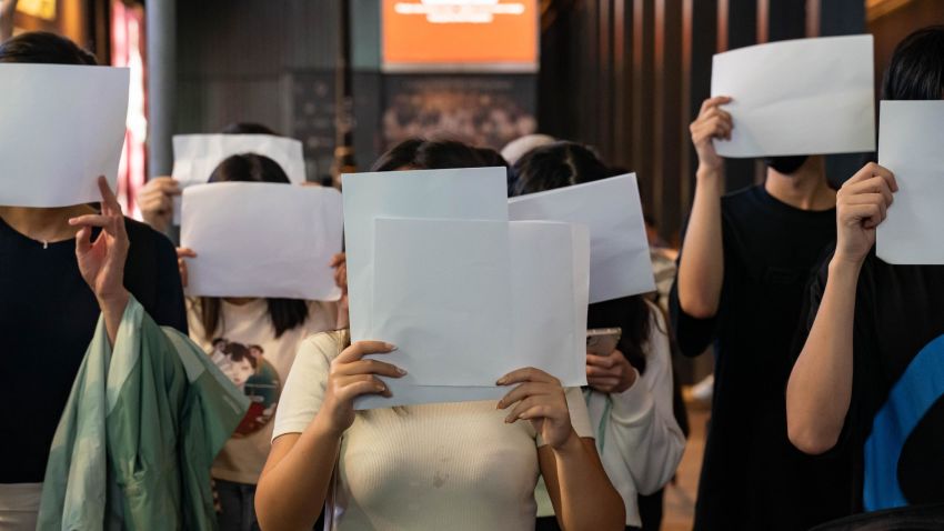 HONG KONG, CHINA - NOVEMBER 28: People hold sheets of blank paper in protest of COVID restriction in mainland as police setup cordon during a vigil in the central district on November 28, 2022 in Hong Kong, China. Protesters took to the streets in multiple Chinese cities after a deadly apartment fire in Xinjiang province sparked a national outcry as many blamed COVID restrictions for the deaths. (Photo by Anthony Kwan/Getty Images)