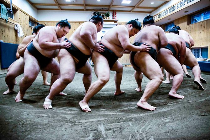 Wrestlers partake in a practice drill at their 'beya', a stable where the athletes live and train.