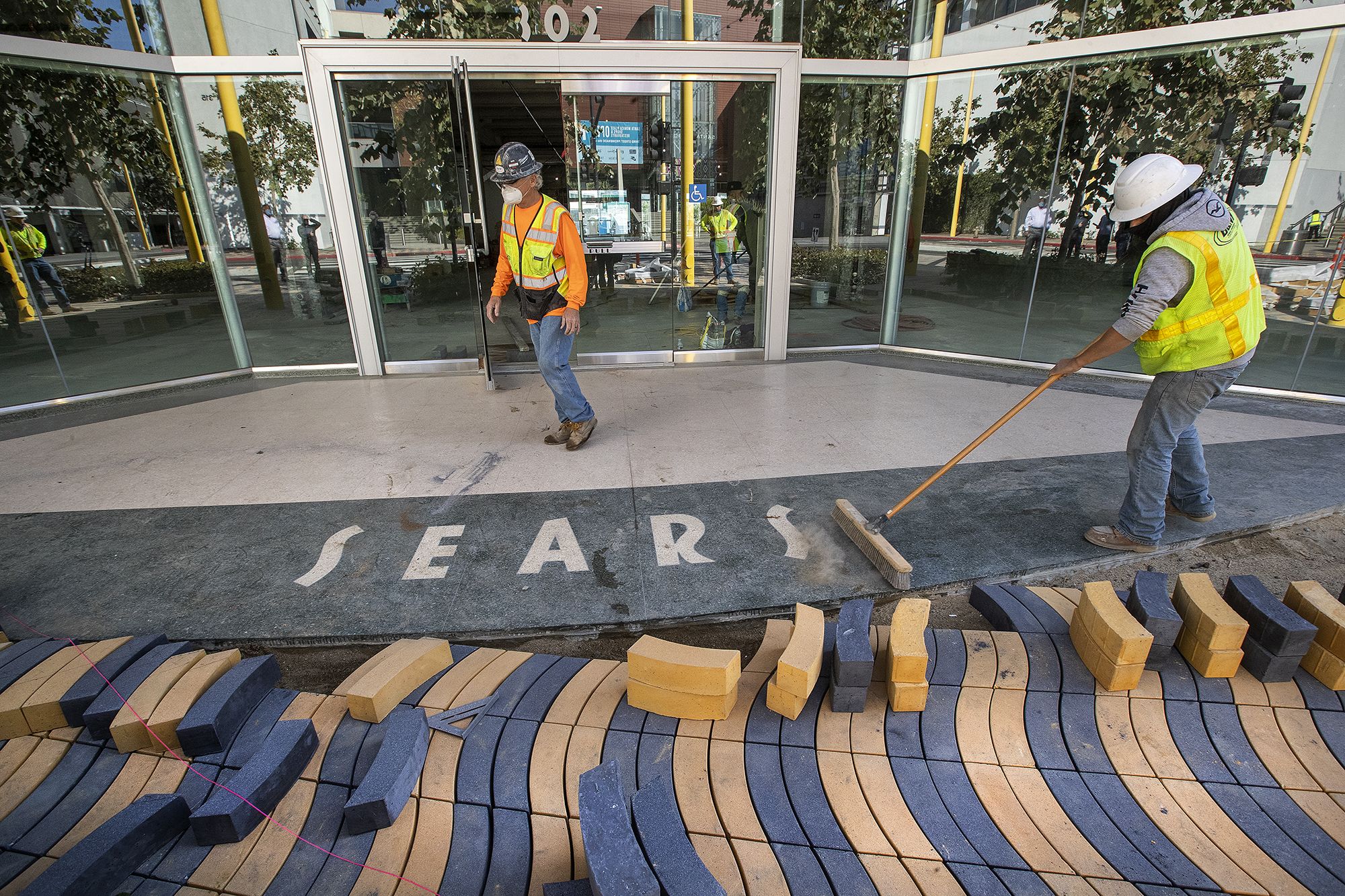 Cesar Villasenor, right, sweeps away dirt in front of a vacant Sears store in Santa Monica, California, in 2020.