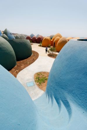 <strong>Presence in Hormuz 2, Hormuz, Iran, ZAV Architects (2020) -- </strong>These colorful buildings are crafted using the <a href="index.php?page=&url=https%3A%2F%2Fwww.calearth.org%2Fintro-superadobe" target="_blank" target="_blank">SuperAdobe</a> system by non-profit CalEarth. The method for building these domed structures was pioneered by renowned architect Nader Khalili. Sandbags are filled with moist earth, which are arranged in coils and reinforced with barbed wire and sometimes cement, lime or asphalt between layers. The outside is finished with plaster, protecting the structure from erosion. In Hormuz, 200 buildings were made this way to create a holiday village.