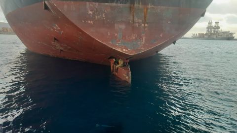 Three stowaways are shown perched on the rudder of the oil and chemical tanker Althini II.