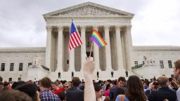 FILE - In this June 26, 2015 file photo, a man holds a U.S. and a rainbow flag outside the Supreme Court in Washington after the court legalized gay marriage nationwide. Court documents show the state of Alaska for years maintains a discriminatory policy that denied some same-sex spouses benefits by wrongly claiming gay marriage was not recognized in Alaska, long after courts ordered they be recognized. (AP Photo/Jacquelyn Martin, File)