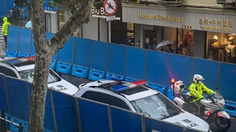 Vehículos policiales patrullan la calle Urumqi de Shanghái, que ha sido completamente bloqueada por altas barricadas luego de las protestas del fin de semana.