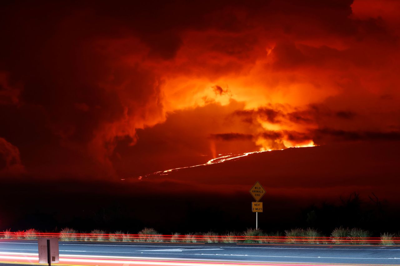 In this long-exposure photo, cars drive down Saddle Road on Monday as Mauna Loa erupts in the distance.