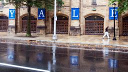ФАЙЛ - Жена минава покрай табела на Йейл, отразена в дъждовната вода на улицата в кампуса на Йейлския университет в Ню Хейвън, Кънектикът, 22 август 2021 г. Университетът Йейл е обвинен във федерално дело, заведено в сряда, 30 ноември 2022 г. на дискриминация срещу студенти с психични увреждания, включително оказване на натиск върху някои да се оттеглят от престижната институция и след това поставяне на „неразумни тежести“ върху онези, които искат да бъдат възстановени. (AP Photo/Ted Shaffrey, File)