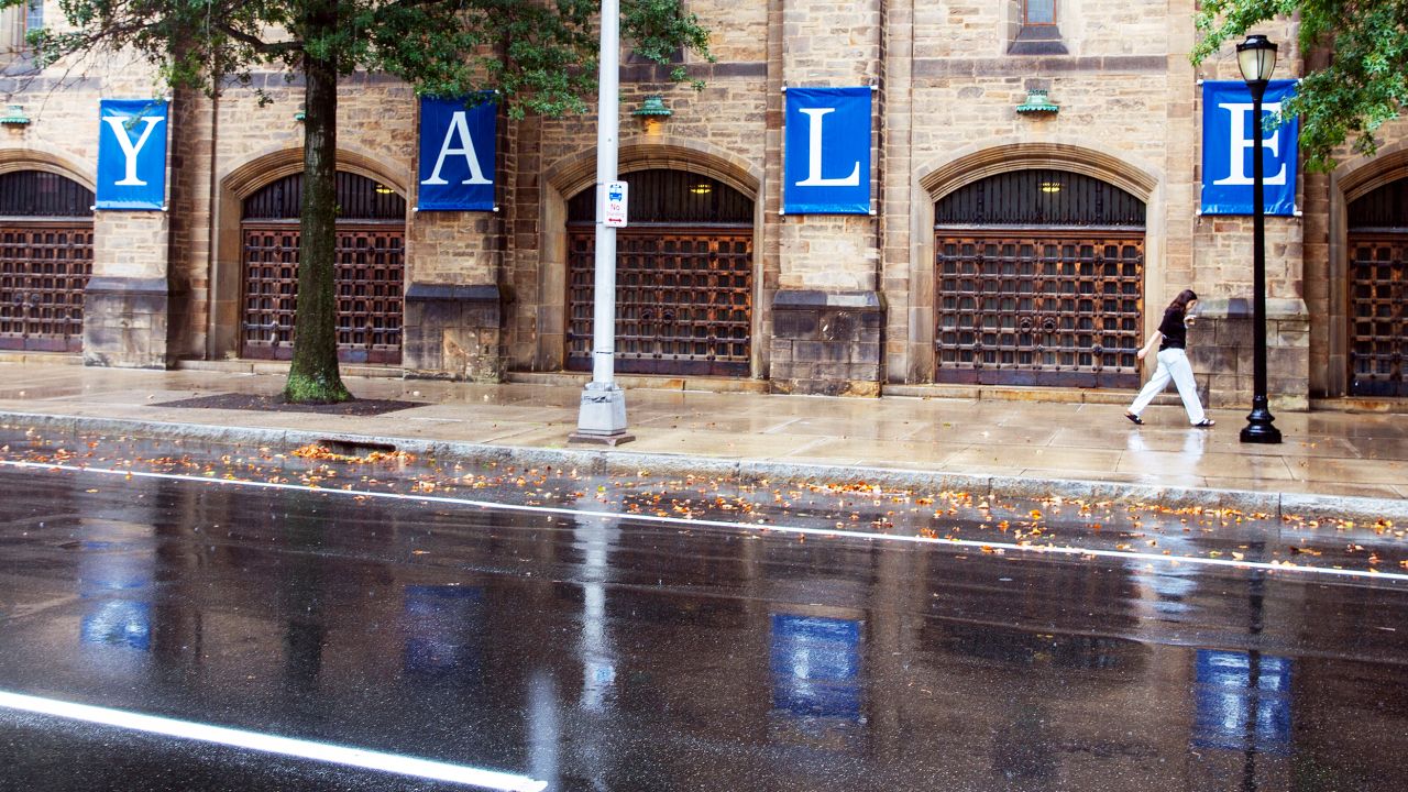 FILE - A woman walks by a Yale sign reflected in the rainwater in the street on the Yale University campus in New Haven, Conn., Aug. 22, 2021. Yale University is being accused in a federal lawsuit filed Wednesday, Nov. 30, 2022, of discriminating against students with mental health disabilities, including pressuring some to withdraw from the prestigious institution and then placing "unreasonable burdens" on those who seek to be reinstated. (AP Photo/Ted Shaffrey, File)