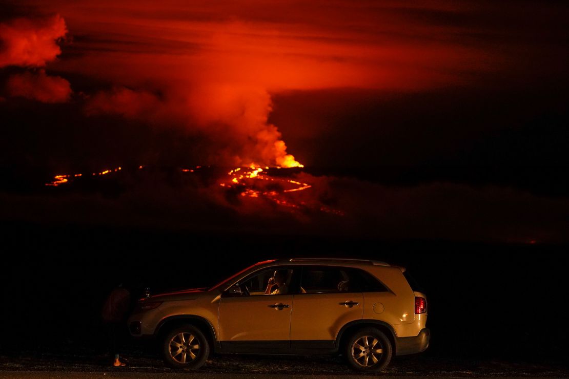 A man talks on a phone in his car alongside Saddle Road as the Mauna Loa volcano erupts Wednesday near Hilo, Hawaii. 