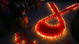 People light candles forming the "Red Ribbon" symbol as they pray for those who have lost their life due to Hiv/Aids, on the eve of World Aids Day in Kathmandu, Nepal November 30, 2022. (Photo by Sunil Pradhan/NurPhoto via Getty Images)