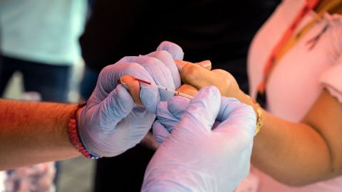 A health worker takes a blood sample from a woman to perform a rapid HIV test during the "Comprehensive Day for the Promotion and Prevention of HIV / AIDS" in the framework of the International Day to Fight HIV-AIDS at the Morelos square in Caracas on December 3, 2021. (Photo by Yuri CORTEZ / AFP) (Photo by YURI CORTEZ/AFP via Getty Images)