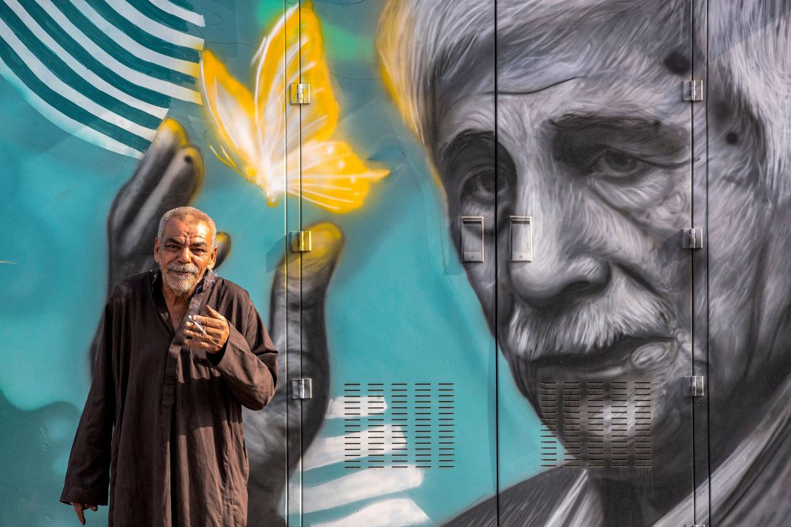 A man stands before a mural depicting Iraqi poet Kazem al-Hajjaj, drawn on an electricity control unit, in the Ashar area of Iraq's southern city of Basra on Thursday