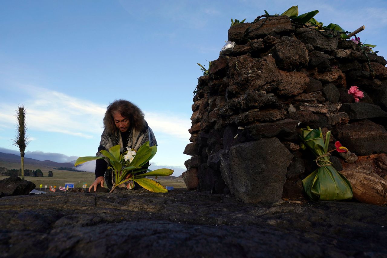 Illona Ilae, a Native Hawaiian from Kailua-Kona, leaves an offering in front of an altar below the volcano on Thursday. For many Native Hawaiians, Mauna Loa's eruption is a time to pray, make offerings and honor both the natural and spiritual worlds.