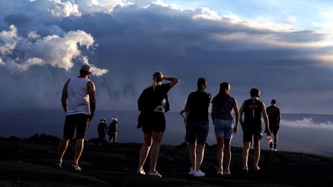 People stand on lava rock from a previous eruption near the Mauna Loa volcano, which erupted near Hilo, Hawaii on Wednesday. 