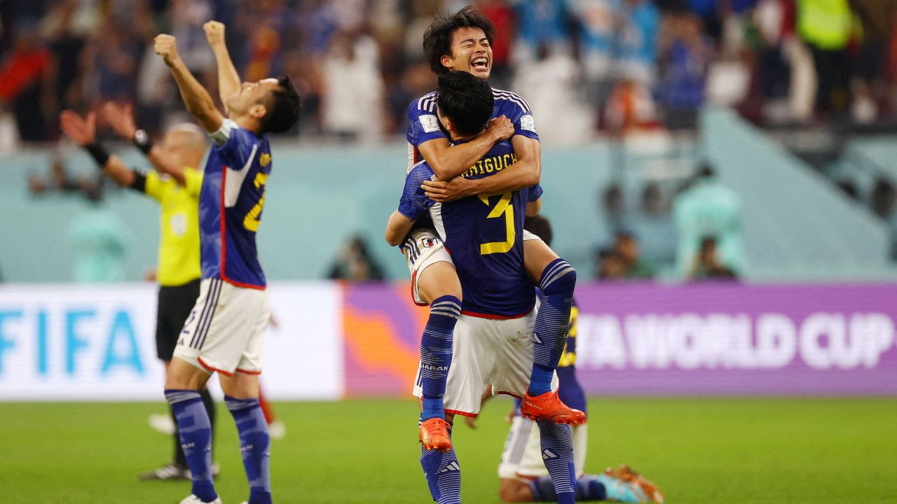 Japan players celebrate reaching the knockout stages after beating Spain.  