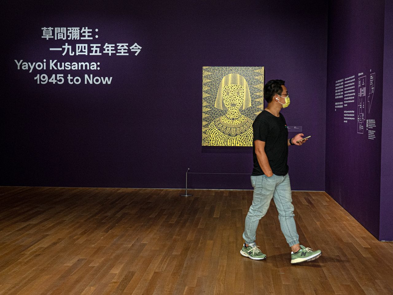 A visitor walks past a self-portrait of the artist.