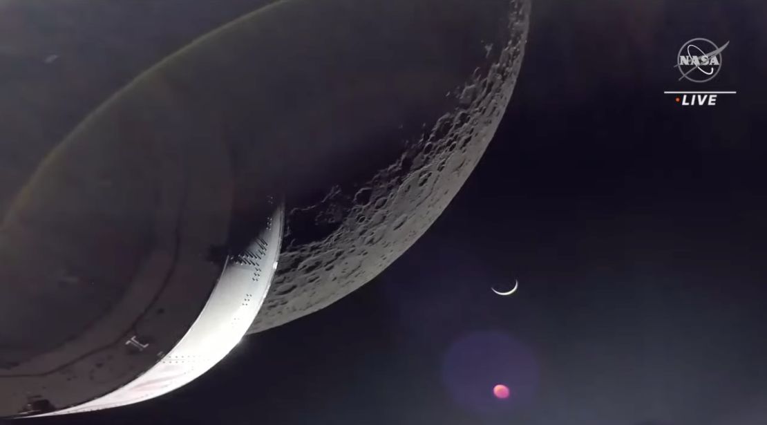 The Orion capsule captures a view of the lunar surface, with Earth in the background lit in the shape of a crescent by the sun.