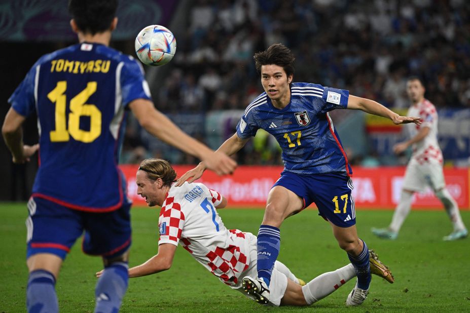 Croatian midfielder Lovro Majer falls near Japanese midfielder Ao Tanaka.